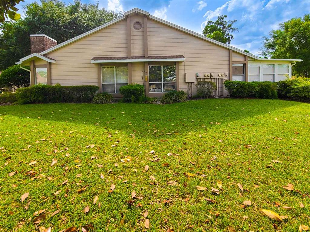 A beige single-story house with a brick chimney and a large front lawn — 2321 SE 19TH CIRCLE, OCALA, FL