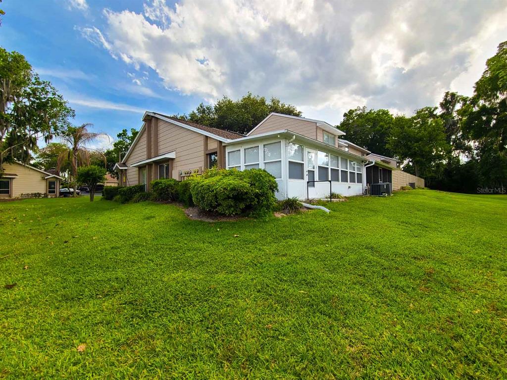 A side view of a house with beige siding and a white enclosed sunroom — 2321 SE 19TH CIRCLE, OCALA, FL