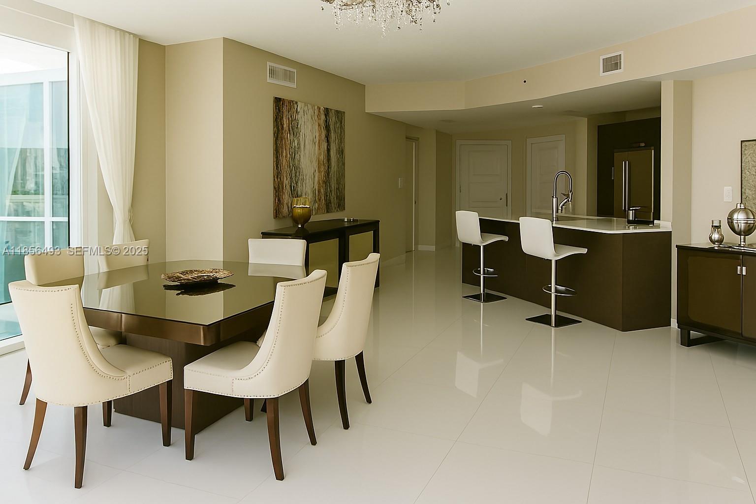 A dining area with a glass table and white chairs opens to a modern kitchen — 250 Sunny Isles Blvd # 1506, Sunny Isles Beach FL 33160, SUNNY ISLES BEACH, FL
