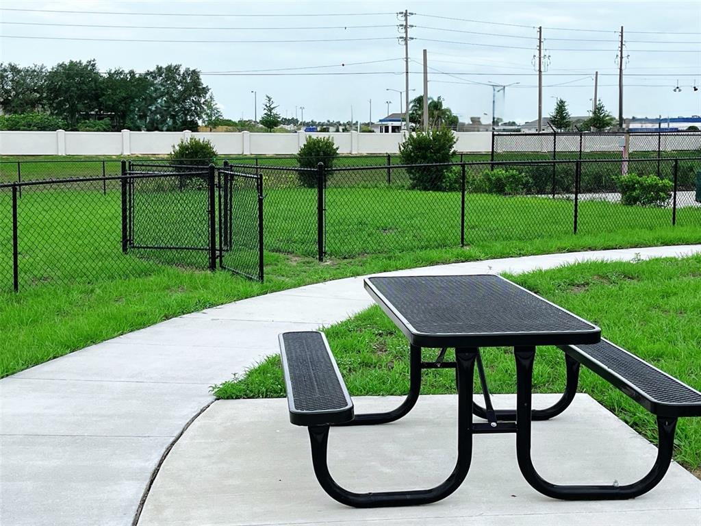 A black metal picnic table sits on a concrete path in a fenced outdoor area — 702 GINGER DRIVE, HAINES CITY, FL