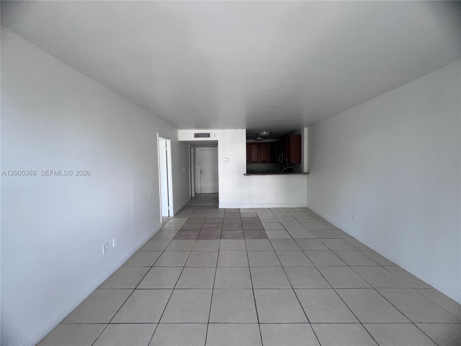 This room features white walls, light-colored floor tiles, and an open kitchen area — 496 NW 165th St Rd # 414, Miami FL 33169, MIAMI, FL