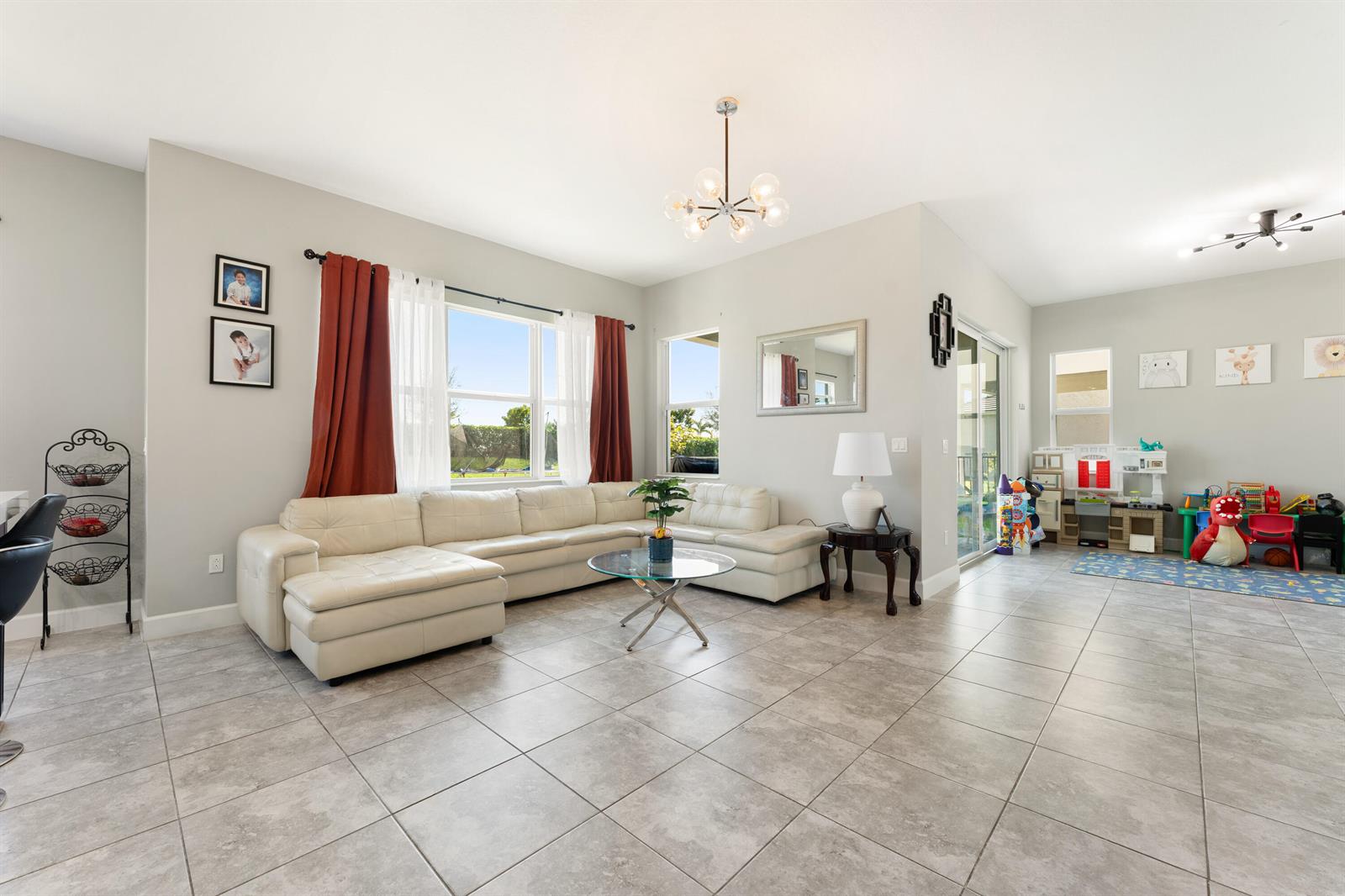 A living room features a white sectional sofa, tile flooring, and a designated play area — 5446 Macoon Way, Westlake FL 33470, WESTLAKE, FL