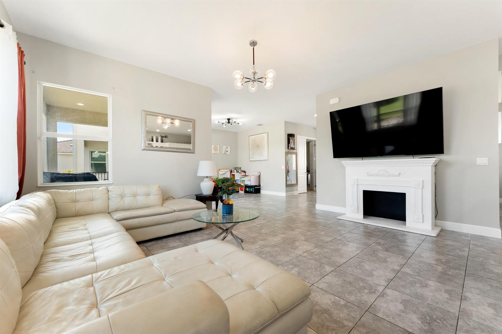 A living room features a white sectional sofa, a fireplace with a television, and tile flooring — 5446 Macoon Way, Westlake FL 33470, WESTLAKE, FL