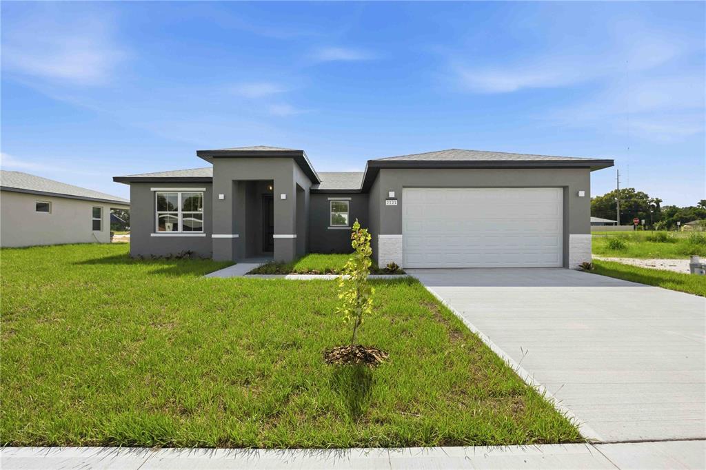 A modern single-story house with a gray exterior, white stone accents, and a two-car garage — 2121 RIVER HAWK LOOP, WINTER HAVEN, FL