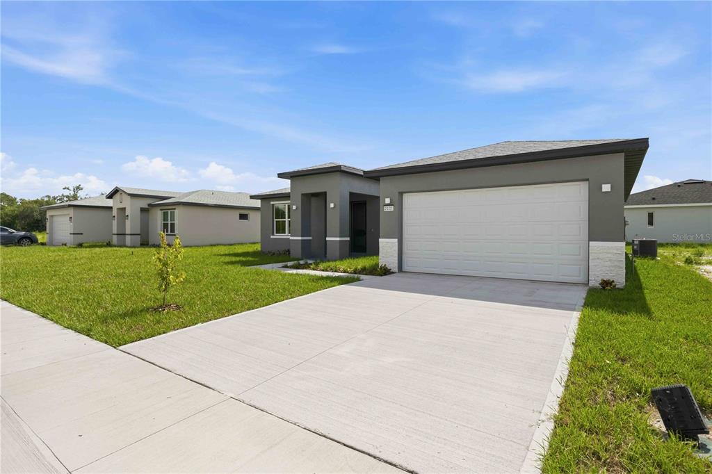 A modern single-story house with a gray exterior, two-car garage, and a concrete driveway — 2121 RIVER HAWK LOOP, WINTER HAVEN, FL