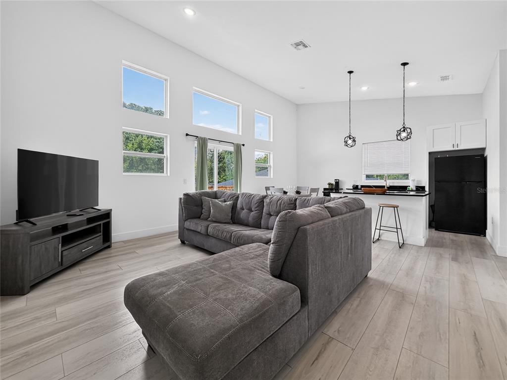 A living room with a gray sectional sofa, television, and an open kitchen with island — 126 1ST STREET, ORLANDO, FL