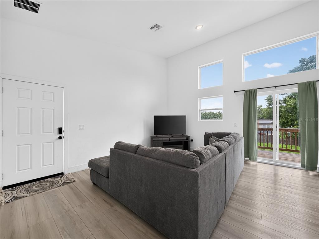 A living room features a grey sectional sofa, a television, and sliding glass doors — 126 1ST STREET, ORLANDO, FL