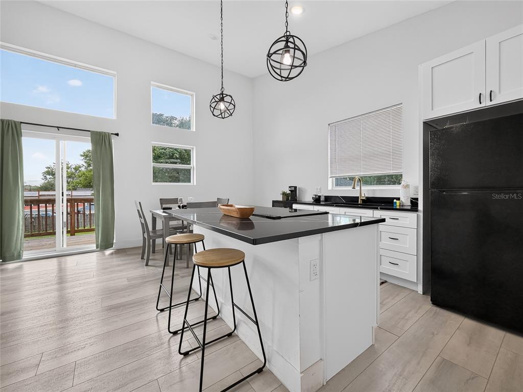 A modern kitchen features a black island with bar stools, white cabinetry, and wood flooring — 126 1ST STREET, ORLANDO, FL