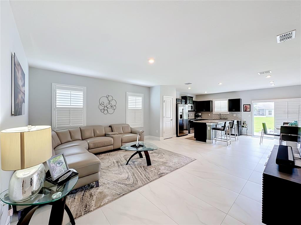 A living room with a beige sectional sofa opens into a kitchen with dark cabinets — 3628 SAPPHIRE HOLLOW WAY, FORT PIERCE, FL