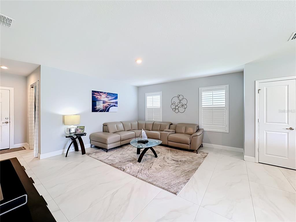 A living room features a beige sectional sofa, a glass coffee table, and tile flooring — 3628 SAPPHIRE HOLLOW WAY, FORT PIERCE, FL
