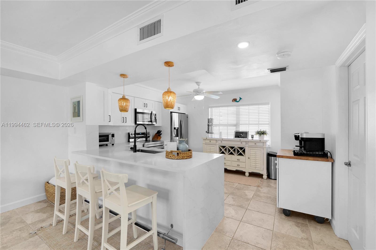 A living room features a gray sectional sofa, a kitchen island with bar stools, and stairs — 335 Virginia St, Hollywood FL 33019, HOLLYWOOD, FL
