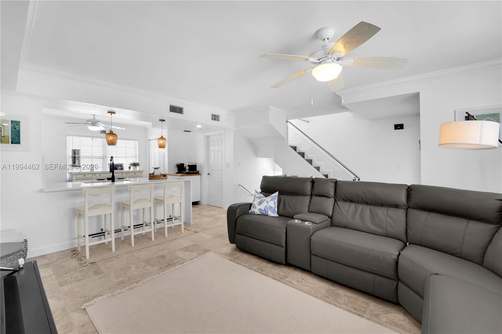 A white kitchen features a breakfast bar with three stools and two hanging pendant lights — 335 Virginia St, Hollywood FL 33019, HOLLYWOOD, FL