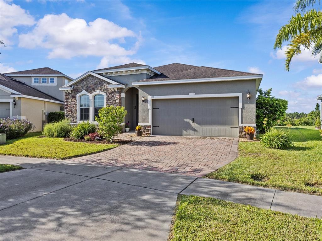 A single-story house features a stone facade, a two-car garage, and a paved driveway — 120 WHIRLAWAY DRIVE, DAVENPORT, FL