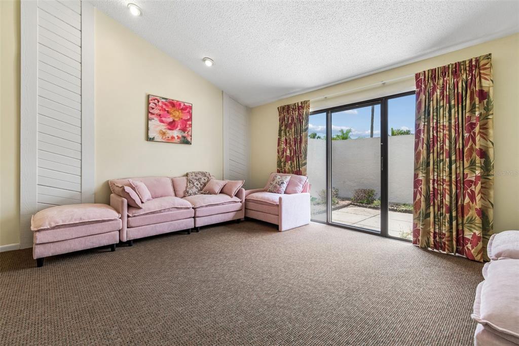 A living room features pink seating, beige carpet, and a sliding glass door to a patio — 4243 OAK LOOP UNIT 35, MULBERRY, FL