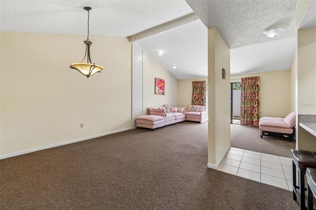A living room with beige carpet, vaulted ceilings, and pink furniture — 4243 OAK LOOP UNIT 35, MULBERRY, FL
