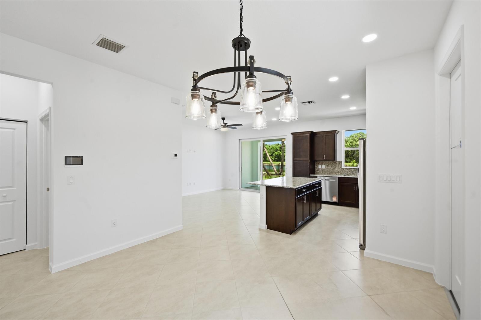 An open-concept kitchen and dining area features dark wood cabinets, granite countertops, and tile flooring — 4332 Brookgreen Square, Westlake FL 33470, WESTLAKE, FL