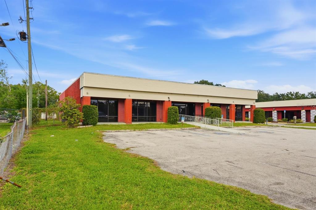 A single-story commercial building with red brick walls and a large paved parking lot — 4830 US HIGHWAY 92 E, LAKELAND, FL
