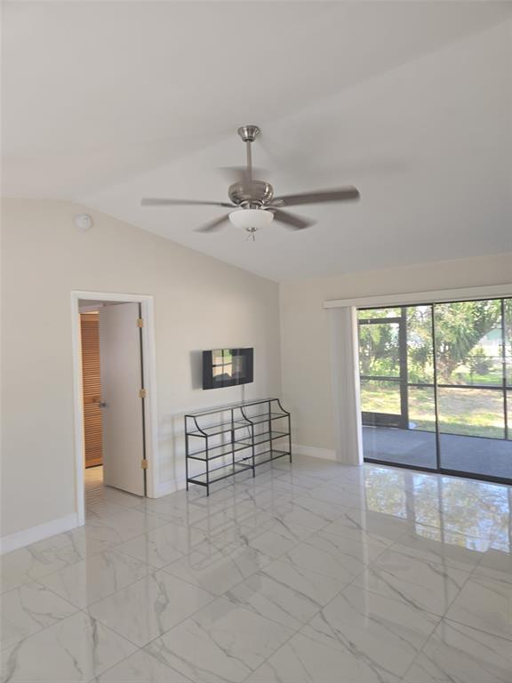 A bright room features white marble-look tile flooring, a ceiling fan, and a sliding glass door — 1805 CORAL POINT DRIVE, CAPE CORAL, FL