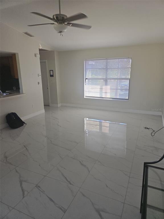 A living room features white marble-look tile flooring, a ceiling fan, and a large window — 1805 CORAL POINT DRIVE, CAPE CORAL, FL
