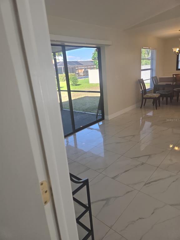 A dining area with white marble-look tile floors leads to a screened-in patio — 1805 CORAL POINT DRIVE, CAPE CORAL, FL