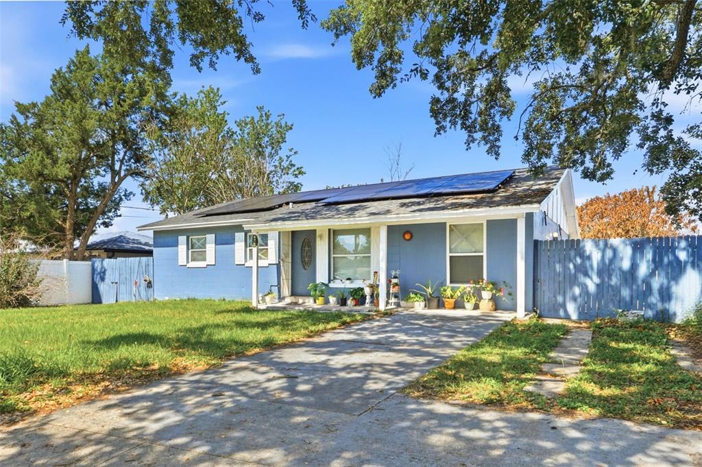 A blue single-story house with a concrete driveway and solar panels on the roof — 6 VIOLA STREET, KISSIMMEE, FL