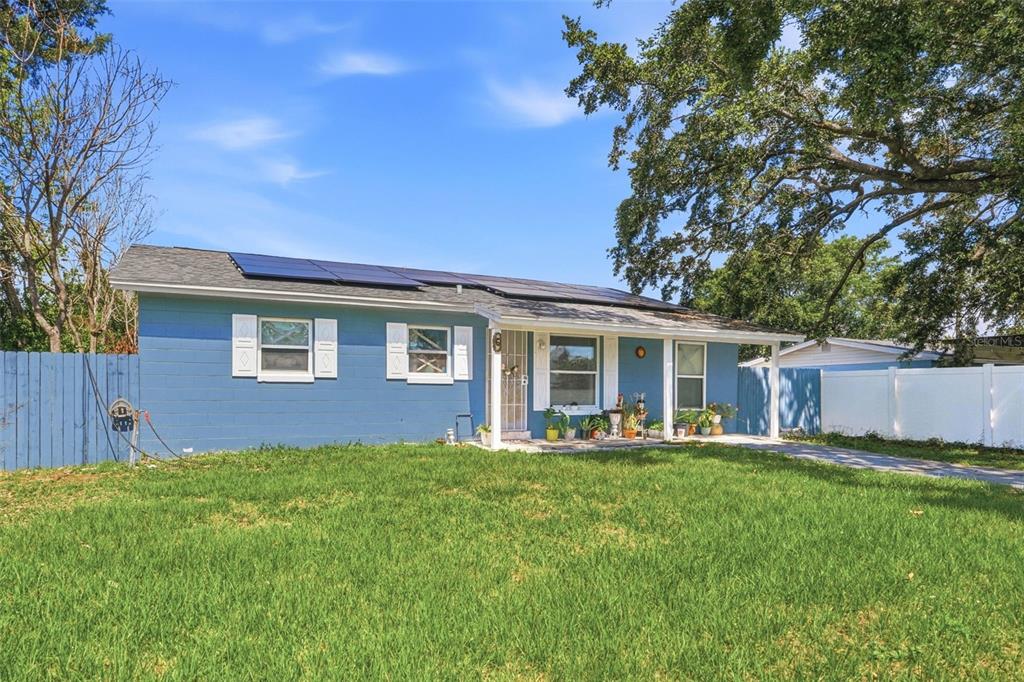 A blue single-story house with a front porch, solar panels, and a grassy lawn — 6 VIOLA STREET, KISSIMMEE, FL