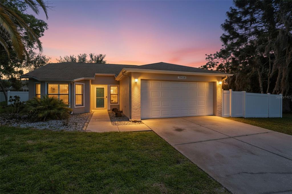 A single-story house with a two-car garage and a concrete driveway at sunset — 10616 BUCKS RUN, NEW PORT RICHEY, FL