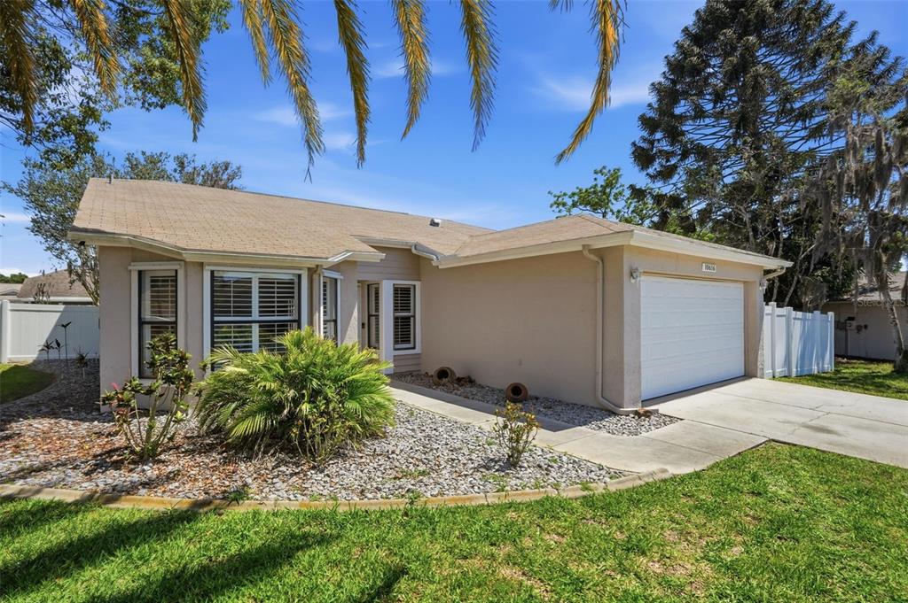 A single-story house with a tan exterior, a two-car garage, and a landscaped front yard — 10616 BUCKS RUN, NEW PORT RICHEY, FL