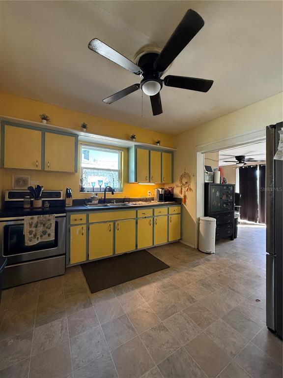 A kitchen features yellow cabinets, a stainless steel stove, and a ceiling fan — 6100 MAIN STREET UNIT A, NEW PORT RICHEY, FL