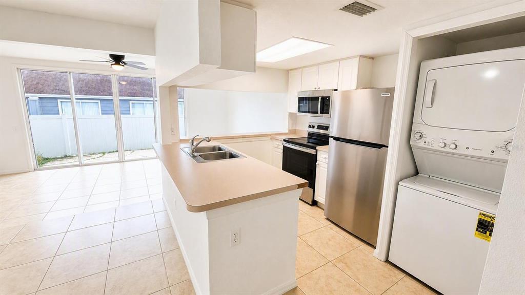 A living room with beige tile flooring features a sunken area and a kitchen pass-through — 225 MANGO DRIVE, DAVENPORT, FL