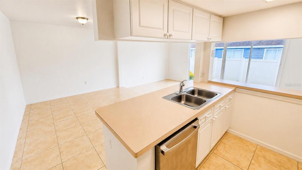 An open-concept kitchen and living area with tile flooring, stainless steel appliances, and sliding doors — 225 MANGO DRIVE, DAVENPORT, FL