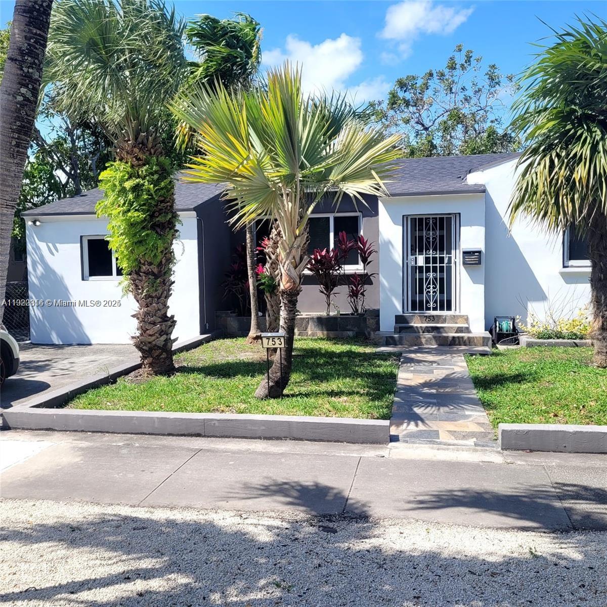 A single-story white house features a stone walkway, palm trees, and a metal security door — 753 NE 81st St, Miami FL 33138, MIAMI, FL