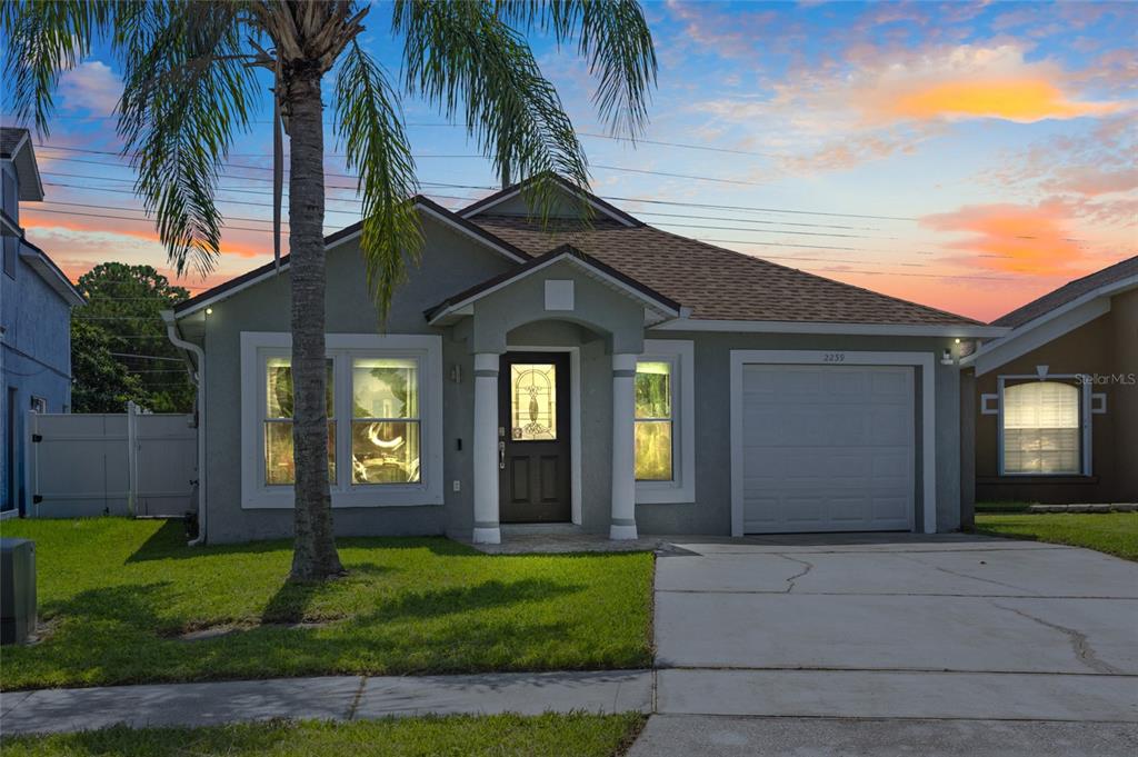 A single-story house with a gray stucco exterior, a front porch, and an attached garage — 2239 SANTA LUCIA STREET, KISSIMMEE, FL
