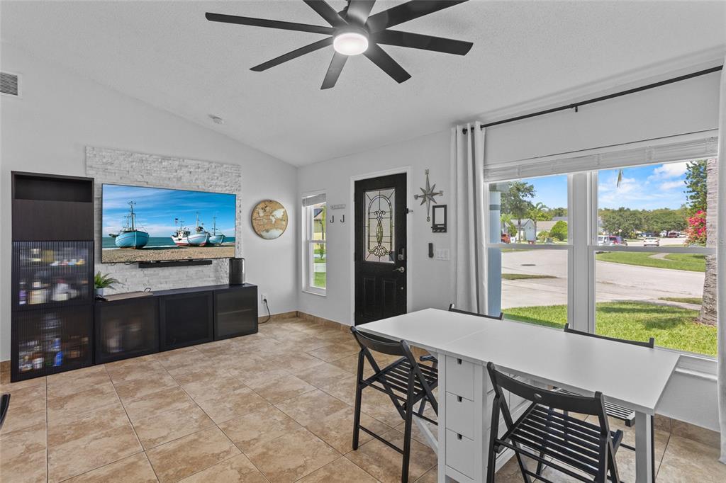 A living and dining area features a stone accent wall, tile flooring, and a ceiling fan — 2239 SANTA LUCIA STREET, KISSIMMEE, FL