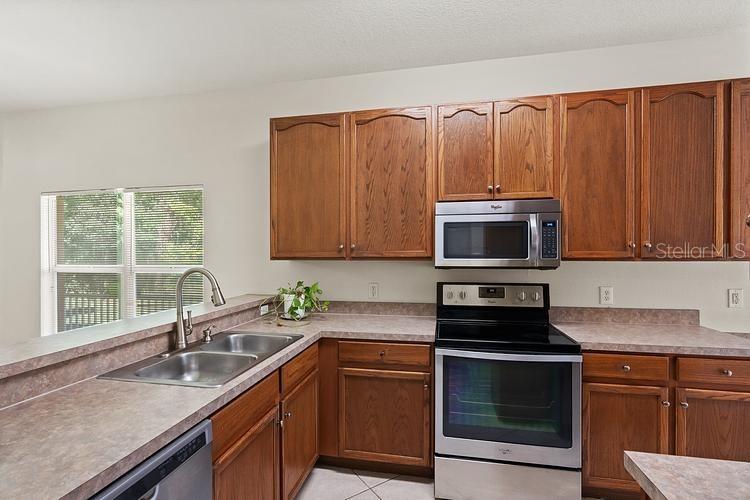 A kitchen features wood cabinets, stainless steel appliances, and laminate countertops — 20221 VINTAGE OAKS PLACE, TAMPA, FL
