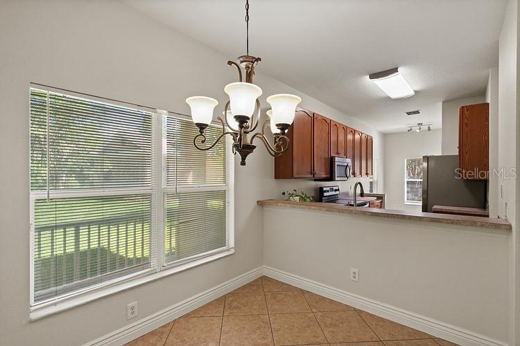 A dining area with tile floors, a chandelier, and a breakfast bar overlooking the kitchen — 20221 VINTAGE OAKS PLACE, TAMPA, FL