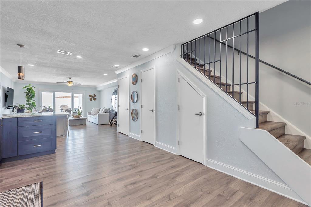 A kitchen and living area with wood-look flooring, a blue island, and a staircase — 5172 COQUINA KEY DRIVE SE, ST PETERSBURG, FL