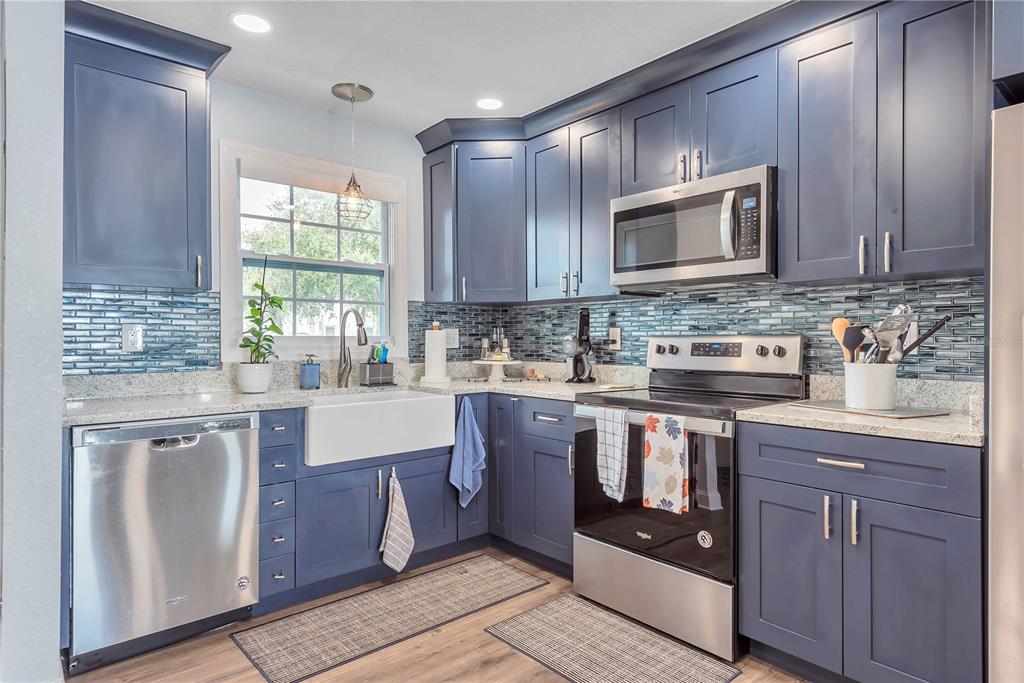 A kitchen with blue cabinets, stainless steel appliances, a farmhouse sink, and a tiled backsplash — 5172 COQUINA KEY DRIVE SE, ST PETERSBURG, FL