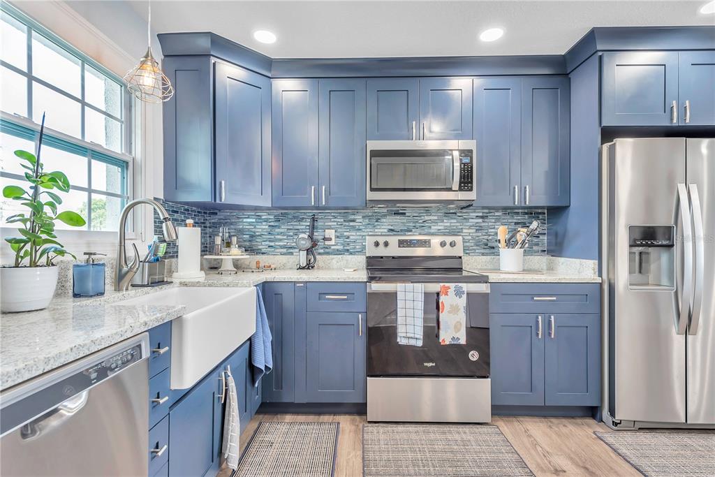 A kitchen features blue cabinets, stainless steel appliances, a farmhouse sink, and a tiled backsplash — 5172 COQUINA KEY DRIVE SE, ST PETERSBURG, FL