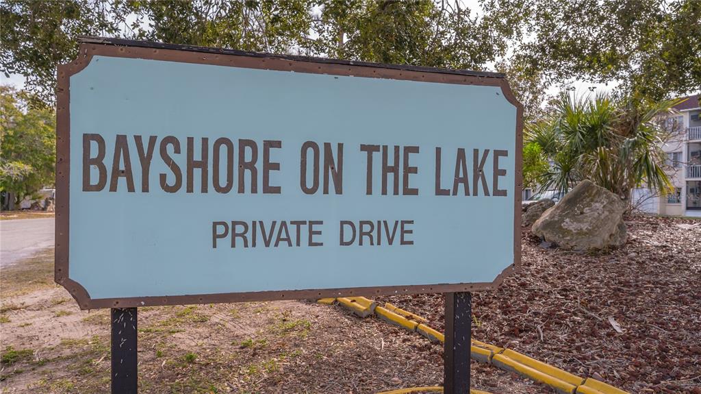 A sign for Bayshore on the Lake stands on a private drive near a building — 3845 LAKE BAYSHORE DRIVE UNIT F103, BRADENTON, FL