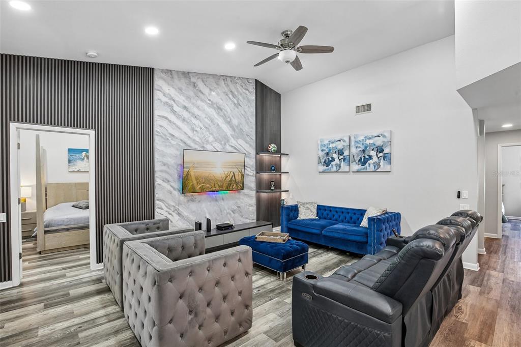 A living room features a marble fireplace wall, gray wood flooring, and blue velvet furniture — 3058 LANDMARK BOULEVARD UNIT 1204, PALM HARBOR, FL