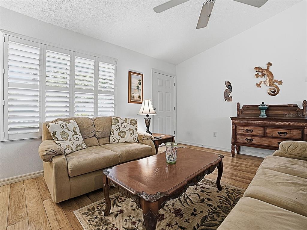 A living room features two beige sofas, a wooden coffee table, and plantation shutters — 2189 CRAWFORD COURT, THE VILLAGES, FL