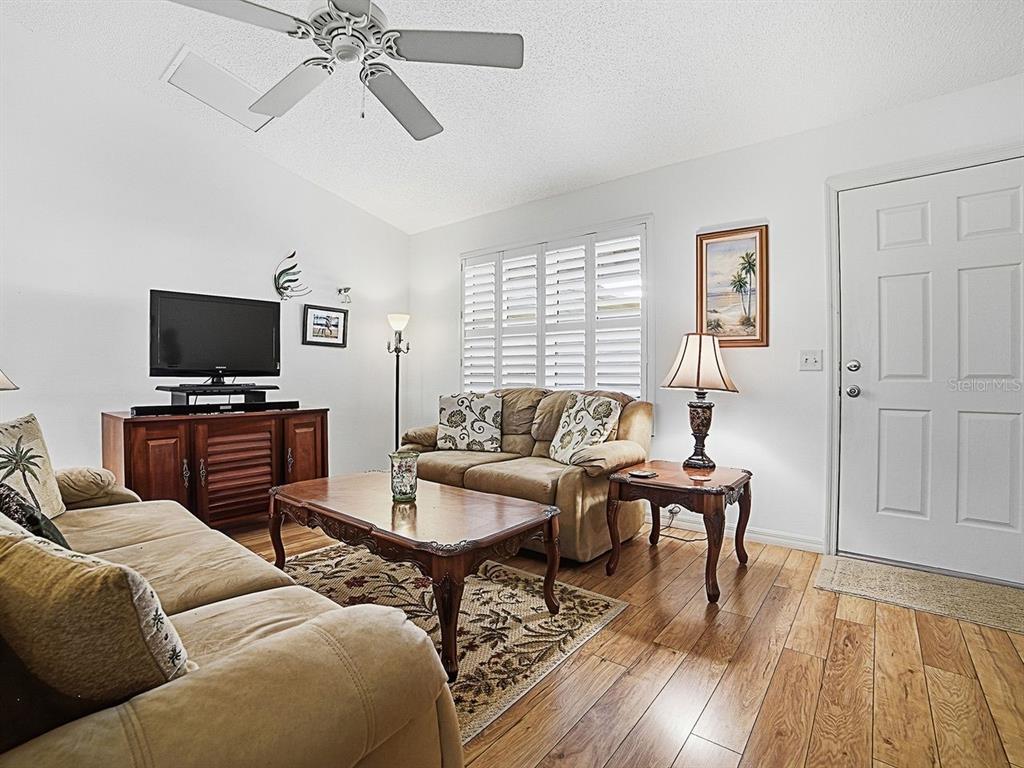A living room features two tan sofas, a wood coffee table, and a ceiling fan — 2189 CRAWFORD COURT, THE VILLAGES, FL