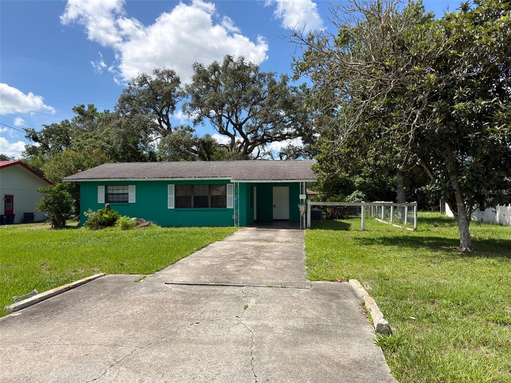 A teal, single-story house with a concrete driveway and a large tree in the yard — 21160 SW HONEYSUCKLE STREET, DUNNELLON, FL