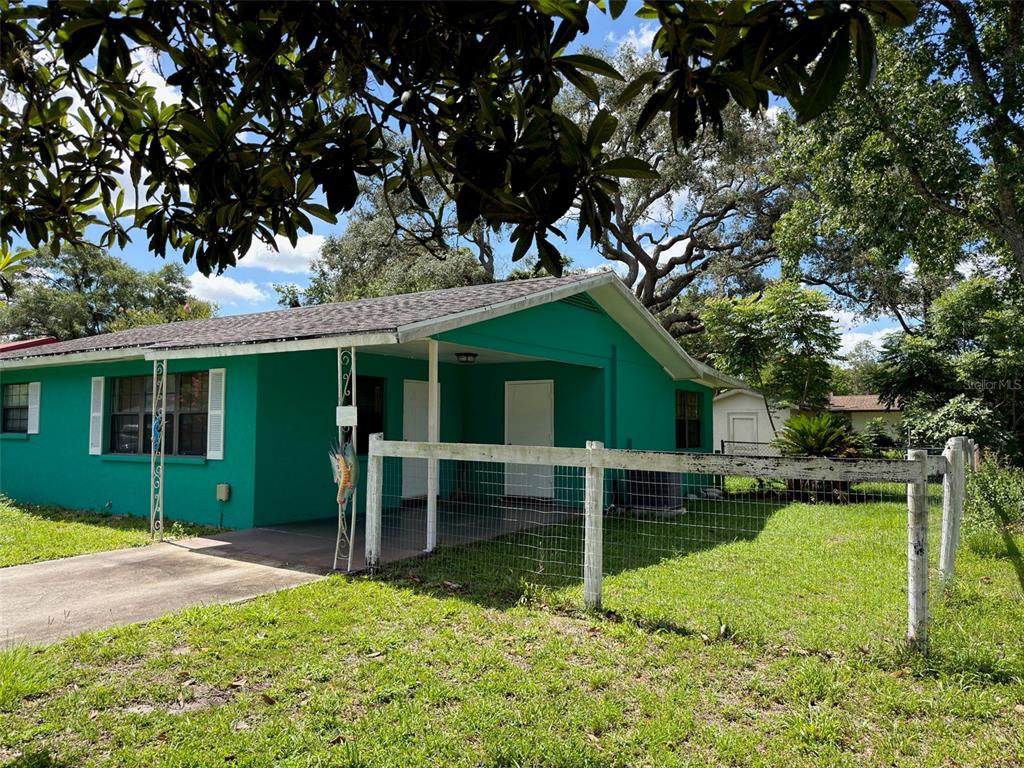 A teal single-story house features a covered porch and a white wire fence — 21160 SW HONEYSUCKLE STREET, DUNNELLON, FL
