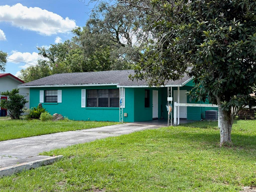 A bright teal, single-story house with a concrete driveway and a large tree in front — 21160 SW HONEYSUCKLE STREET, DUNNELLON, FL
