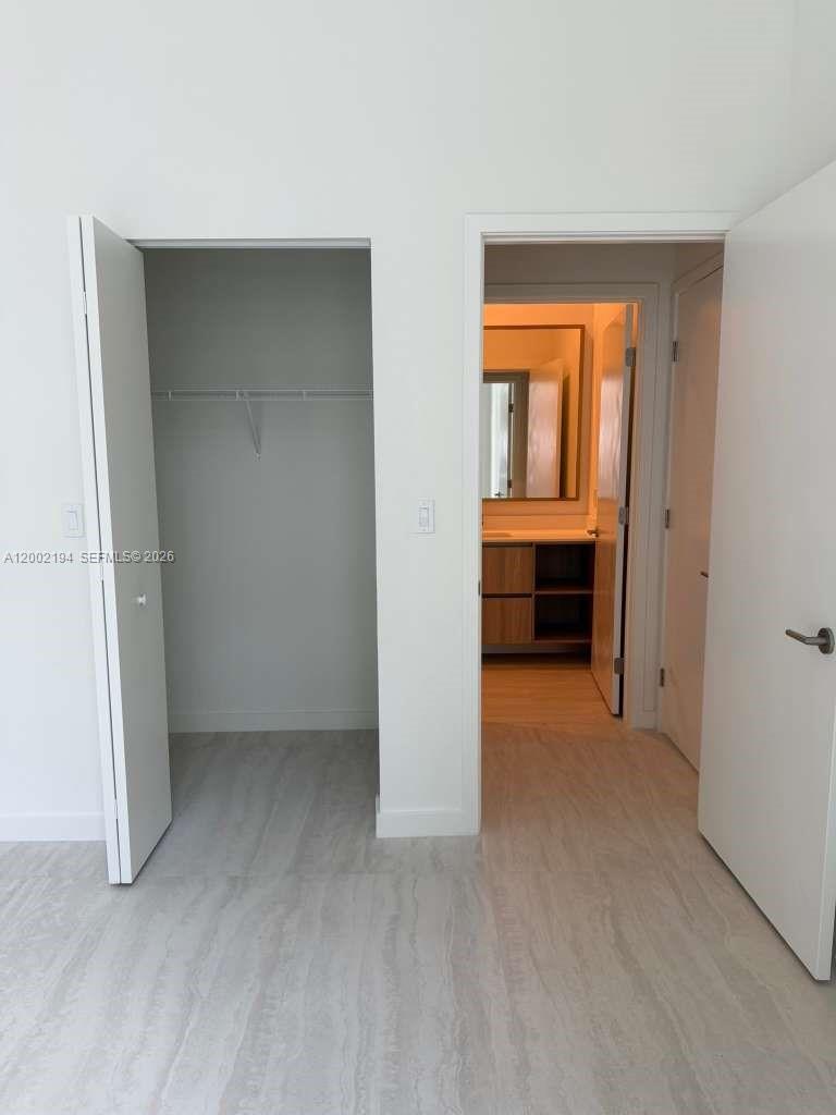 A bedroom features a closet and an open doorway leading into a bathroom — 77 SE 5th street # 1011, Miami FL 33131, MIAMI, FL