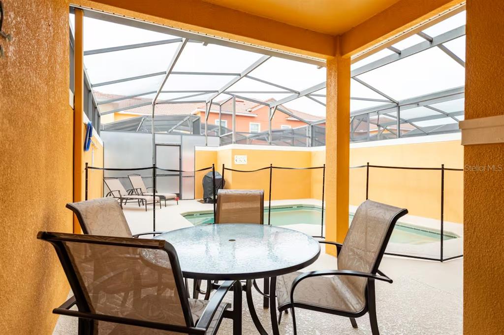 A covered patio features a dining set, a safety fence, and a small swimming pool — 8977 COCO PALM ROAD, KISSIMMEE, FL