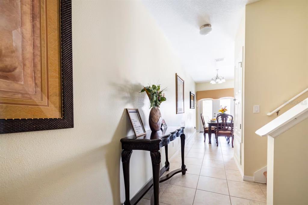 A tiled hallway leads to a dining area with a dark wood console table — 8977 COCO PALM ROAD, KISSIMMEE, FL