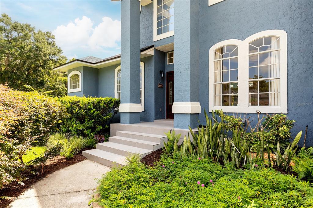 A blue two-story house features a front porch with columns and arched windows — 1153 OAK TREE CIRCLE, ALTAMONTE SPRINGS, FL